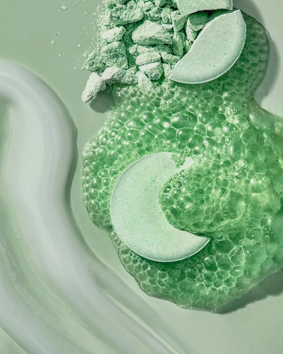 Green Detox pods fizzing into foam on a green surface