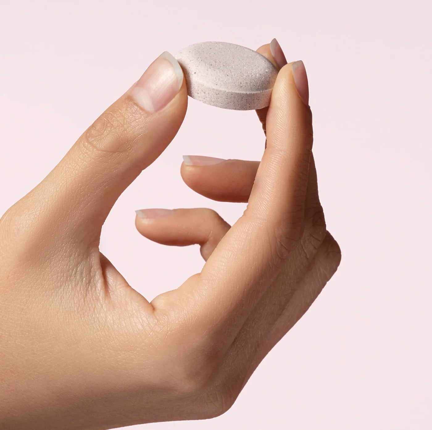 A hand holding a pale pink Illuminate pod