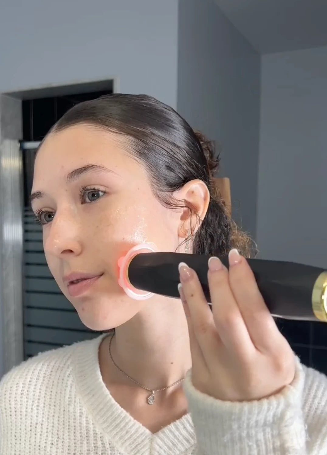 A woman gliding The Facial Pen along her cheek with the red light on